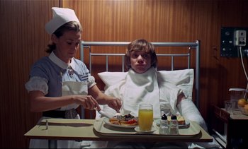 Movie still from “A Clockwork Orange” (1971), directed by Stanley Kubrick – A woman in a hospital bed with a tray of food in front of a patient; Medium shot, Low angle
