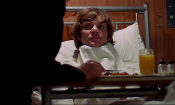 Movie still from “A Clockwork Orange” (1971), directed by Stanley Kubrick – A person in a hospital bed with a tray of food in front of him; Medium shot, Low angle