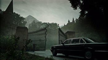 Movie still from “A Cure for Wellness” (2016), directed by Gore Verbinski – A car parked on the side of the road near a gate; Extreme Wide shot, Low angle