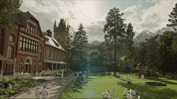 Movie still from “A Cure for Wellness” (2016), directed by Gore Verbinski – People are sitting in the grass in front of a building; Extreme Wide shot, High angle