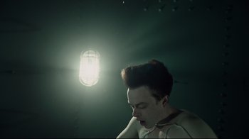 A young man with short brown hair is looking at a light