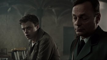 Movie still from “A Cure for Wellness” (2016), directed by Gore Verbinski – Two men are standing next to each other in a room; Close Up shot, Over the shoulder angle