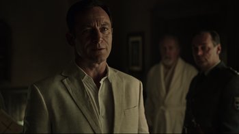 Movie still from “A Cure for Wellness” (2016), directed by Gore Verbinski – A man in a white suit standing next to another man in a white suit; Medium shot, Over the shoulder angle