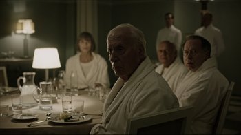 Movie still from “A Cure for Wellness” (2016), directed by Gore Verbinski – A group of people sitting around a table in bathrobes; Medium shot, Over the shoulder angle