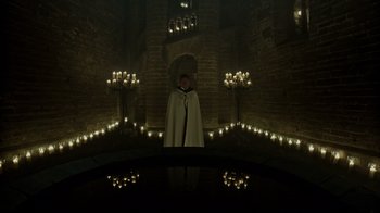 Movie still from “A Cure for Wellness” (2016), directed by Gore Verbinski – A man standing in front of candles in a dark room; Extreme Wide shot, High angle