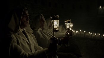Movie still from “A Cure for Wellness” (2016), directed by Gore Verbinski – A group of men in white robes holding lit candles; Medium shot, Low angle