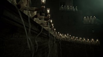 Movie still from “A Cure for Wellness” (2016), directed by Gore Verbinski – A group of people holding lit candles in a dark room; Extreme Wide shot, High angle