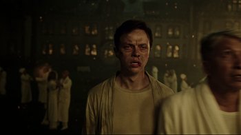 Movie still from “A Cure for Wellness” (2016), directed by Gore Verbinski – A man with a bruised face standing in front of a group of people; Close Up shot, Low angle