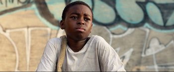 Movie still from “Ambulance” (2022), directed by Michael Bay – A young boy sitting in front of a graffiti wall; Close Up shot, Low angle