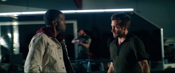 Movie still from “Ambulance” (2022), directed by Michael Bay – Two men are standing in a room talking to each other; Medium shot, Over the shoulder angle