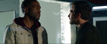 Movie still from “Ambulance” (2022), directed by Michael Bay – Two men standing next to each other in front of a window; Close Up shot, Over the shoulder angle