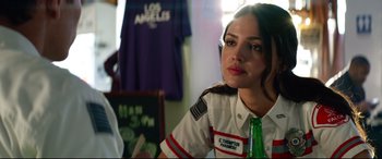 Movie still from “Ambulance” (2022), directed by Michael Bay – A woman sitting at a table with a bottle of beer; Close Up shot, Over the shoulder angle