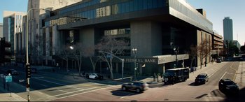 Movie still from “Ambulance” (2022), directed by Michael Bay – A car driving down a street next to a building; Extreme Wide shot, High angle