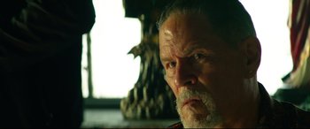 Movie still from “Ambulance” (2022), directed by Michael Bay – An older man with a beard and mustache; Close Up shot, Over the shoulder angle