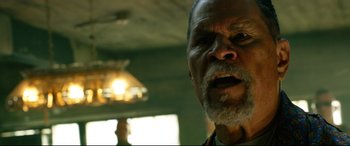 Movie still from “Ambulance” (2022), directed by Michael Bay – An old man with a beard and mustache looking at the camera; Close Up shot, Low angle