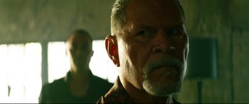 Movie still from “Ambulance” (2022), directed by Michael Bay – An older man with a beard and mustache; Close Up shot, Low angle
