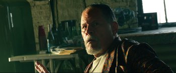 Movie still from “Ambulance” (2022), directed by Michael Bay – An older man with a beard and mustache wearing a robe; Close Up shot, Low angle