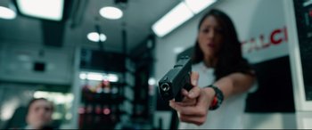 Movie still from “Ambulance” (2022), directed by Michael Bay – A woman is holding a gun in a room; Close Up shot, Low angle