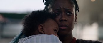Movie still from “Ambulance” (2022), directed by Michael Bay – A woman holding a child in her arms; Close Up shot, Low angle