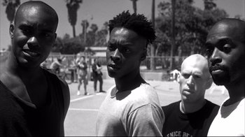 Movie still from “American History X” (1998), directed by Tony Kaye – A black and white photo of a man in a crowd of people; Medium shot, Low angle