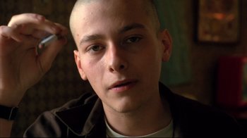 Movie still from “American History X” (1998), directed by Tony Kaye – A man with a shaved head is looking at the camera; Close Up shot, Low angle