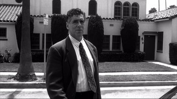 Movie still from “American History X” (1998), directed by Tony Kaye – Black and white photograph of a man wearing a suit and tie; Medium shot, Low angle