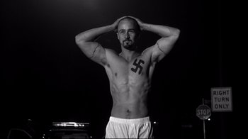Movie still from “American History X” (1998), directed by Tony Kaye – A shirtless man with a nazi symbol tattooed on his chest; Medium shot, Low angle