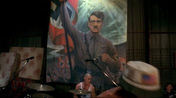 Movie still from “American History X” (1998), directed by Tony Kaye – A painting of adolf hitler in front of a crowd; Medium shot, Low angle