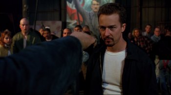 Movie still from “American History X” (1998), directed by Tony Kaye – A man in white shirt and black jacket standing in front of a crowd; Medium shot, Over the shoulder angle