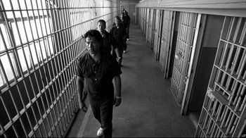 Movie still from “American History X” (1998), directed by Tony Kaye – A group of men walking down a hallway in a jail cell; Wide shot, Low angle
