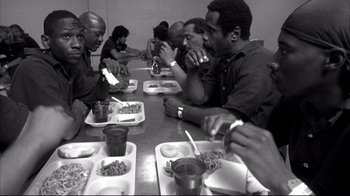 Movie still from “American History X” (1998), directed by Tony Kaye – A group of people sitting at a table with plates of food on it; Medium shot, High angle