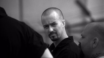 Movie still from “American History X” (1998), directed by Tony Kaye – Black and white photograph of a man with a shaved head; Close Up shot, Over the shoulder angle