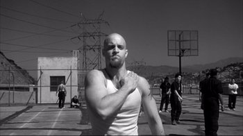 Movie still from “American History X” (1998), directed by Tony Kaye – A man with a shaved head is holding his arm up; Medium shot, Low angle
