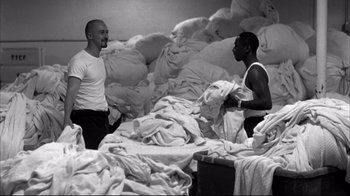Movie still from “American History X” (1998), directed by Tony Kaye – Two men standing next to each other on a bed covered in sheets; Medium shot, High angle