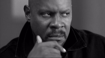 Movie still from “American History X” (1998), directed by Tony Kaye – A black and white photo of a bald man with his hand under his chin; Close Up shot, Low angle