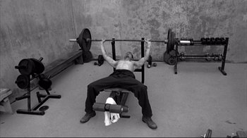 Movie still from “American History X” (1998), directed by Tony Kaye – A man is lifting a barbell in a gym; Medium shot, Low angle