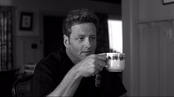 Movie still from “American History X” (1998), directed by Tony Kaye – A black and white photo of a man holding a coffee cup; Close Up shot, Low angle