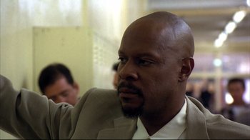 Movie still from “American History X” (1998), directed by Tony Kaye – A man in a suit and tie sitting in front of other people; Close Up shot, Low angle
