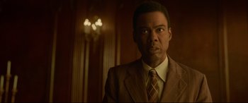 Movie still from “Amsterdam” (2022), directed by David O. Russell – A man wearing a suit and tie in a room; Close Up shot, Low angle