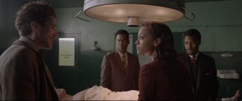 Movie still from “Amsterdam” (2022), directed by David O. Russell – A woman standing next to a man in a room; Medium shot, Over the shoulder angle