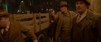 Movie still from “Amsterdam” (2022), directed by David O. Russell – An old man in a hat is holding a gun in his hand; Medium shot, Over the shoulder angle