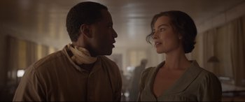 Movie still from “Amsterdam” (2022), directed by David O. Russell – A man and a woman standing next to each other in a room; Close Up shot, Over the shoulder angle