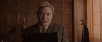 Movie still from “Amsterdam” (2022), directed by David O. Russell – A man in a suit and tie holding a computer; Close Up shot, Low angle