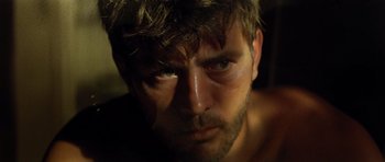 Movie still from “Apocalypse Now” (1979), directed by Francis Ford Coppola – A man's face in a dark room; Close Up shot, Low angle