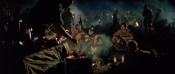 Movie still from “Apocalypse Now” (1979), directed by Francis Ford Coppola – A group of men sitting around a fire; Wide shot, High angle