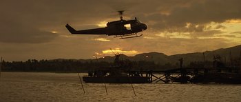 Movie still from “Apocalypse Now” (1979), directed by Francis Ford Coppola – A helicopter flying over a boat in a body of water at sunset; Extreme Wide shot, Low angle