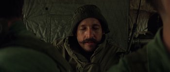 Movie still from “Apocalypse Now” (1979), directed by Francis Ford Coppola – A man with a beard wearing a hat and a jacket; Close Up shot, Over the shoulder angle