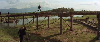 Movie still from “Apocalypse Now” (1979), directed by Francis Ford Coppola – A man walking across a wooden bridge over a river; Extreme Wide shot, Low angle