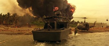 Movie still from “Apocalypse Now” (1979), directed by Francis Ford Coppola – A boat is in the middle of the water near a burning oil field; Extreme Wide shot, Low angle