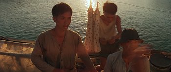 Movie still from “Apocalypse Now” (1979), directed by Francis Ford Coppola – A group of people sitting next to a body of water; Medium shot, Low angle